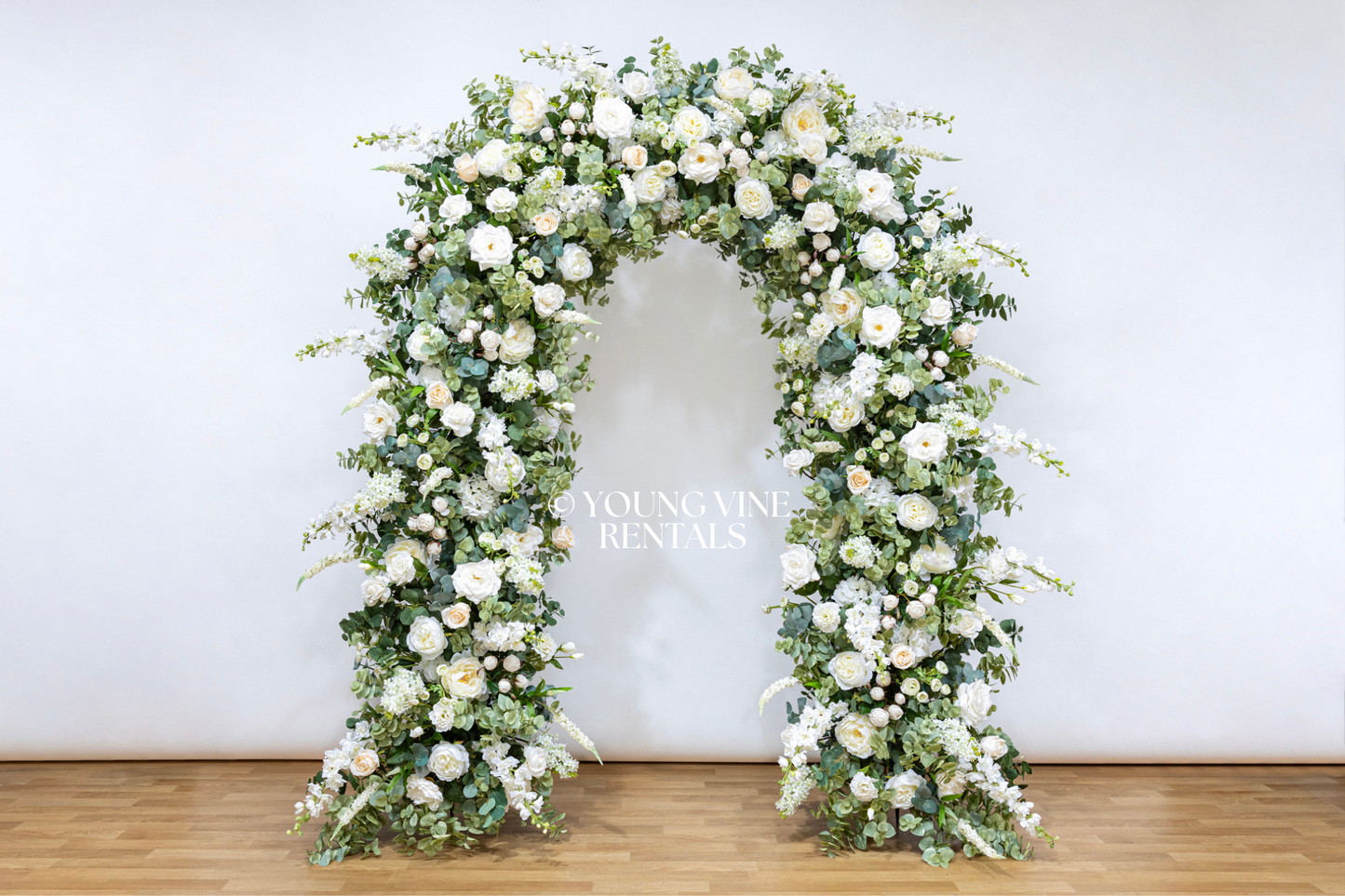 Lush, romantic, U-shaped wedding arbor studded with an abundance of ivory and white flowers and various types of eucalyptus foliage.