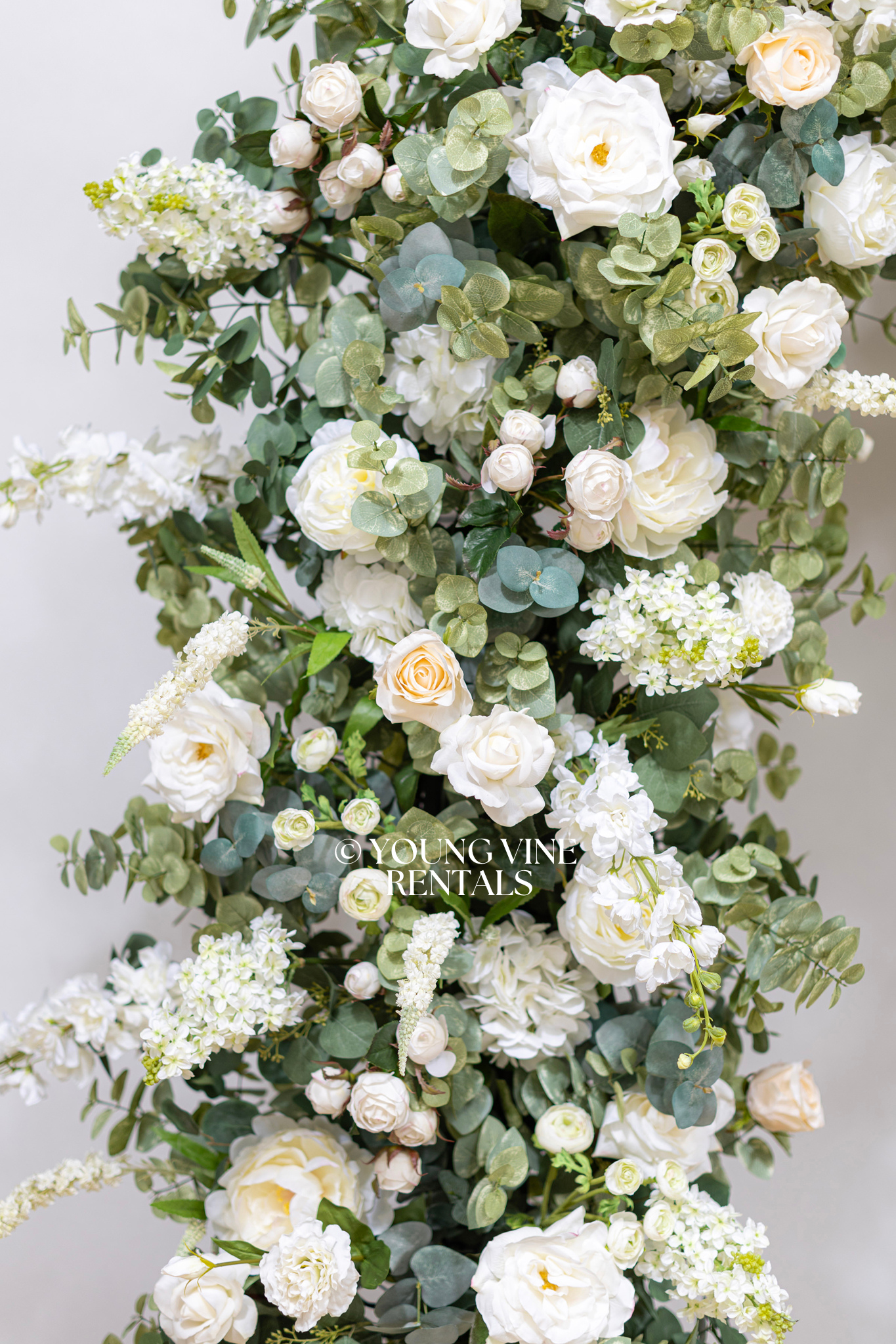 Close-up detail of lush, romantic wedding floral arbor studded with an abundance of ivory and white flowers and various types of eucalyptus foliage.