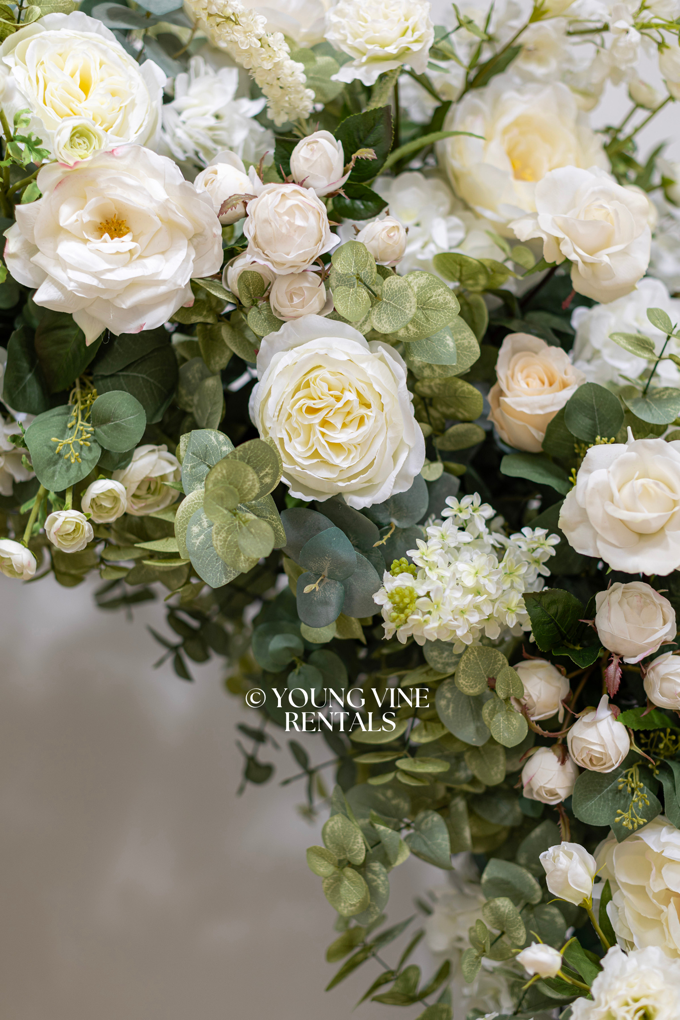 Close-up detail shot of lush, romantic wedding floral arbor studded with an abundance of ivory and white flowers and various types of eucalyptus foliage.