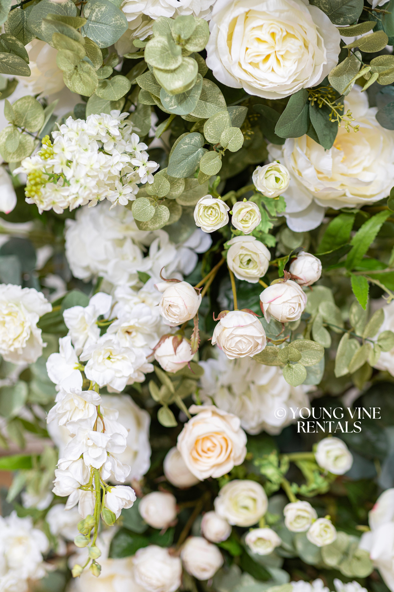 Close-up detail shot of lush, romantic wedding floral arbor studded with an abundance of ivory and white flowers and various types of eucalyptus foliage, with a very delicate and textural overall look.
