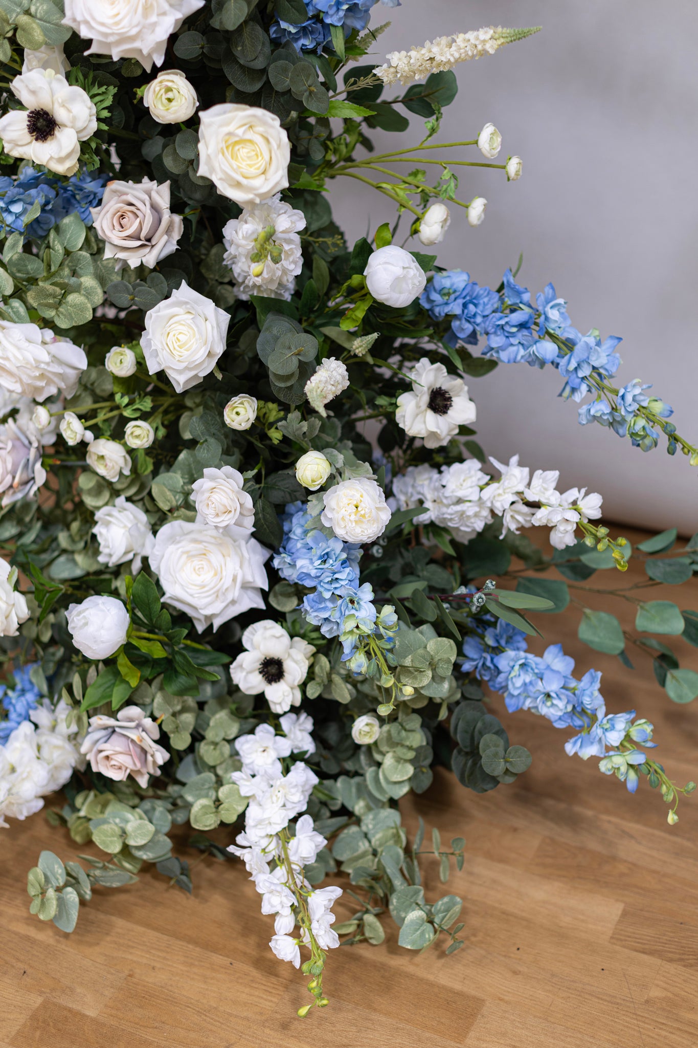 Floral pillars featuring dusty blue delphinium, white anemones, delphinium and roses, accented by eucalyptus foliage.