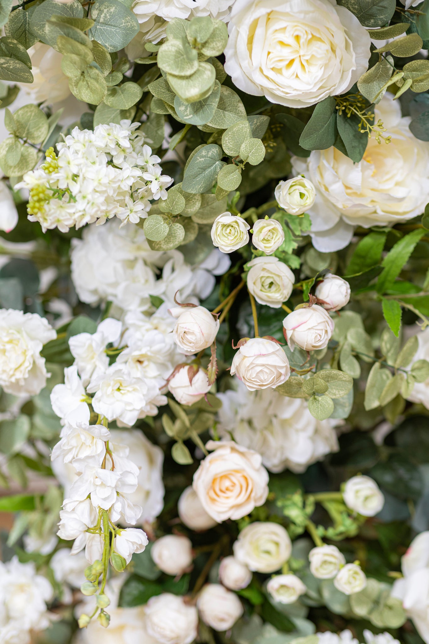 Wedding arbor in a color palette of white, ivory, cream, and pale blush, accented by delicate vines.