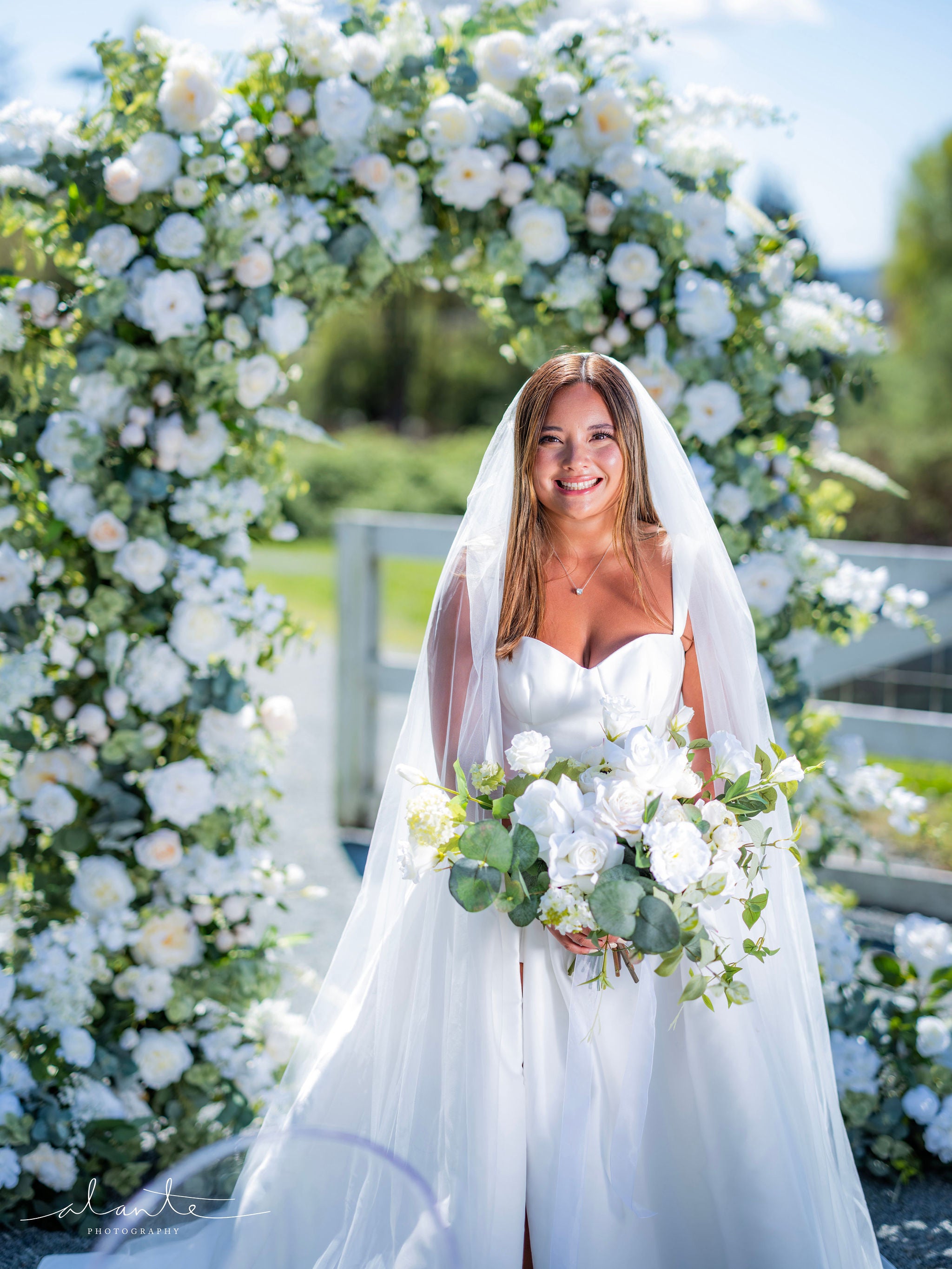 Wedding arbor with an oval shape decorated with ivory, white, and green flowers and foliage